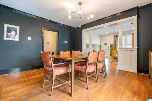 dining space featuring decorative columns, ornamental molding, a notable chandelier, and light wood-type flooring