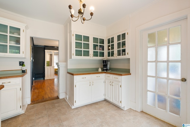 kitchen with an inviting chandelier, white cabinetry, ornamental molding, and light hardwood / wood-style floors