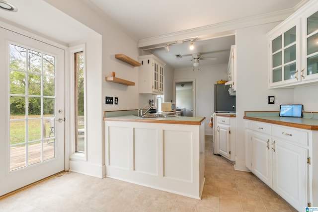 kitchen featuring kitchen peninsula, white cabinetry, ceiling fan, and crown molding