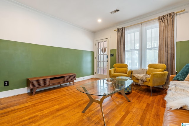 living area with light hardwood / wood-style flooring, plenty of natural light, and crown molding