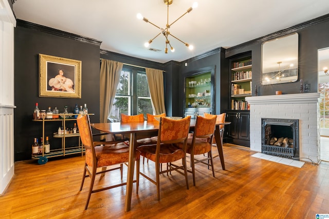 dining room featuring crown molding, hardwood / wood-style floors, and a brick fireplace