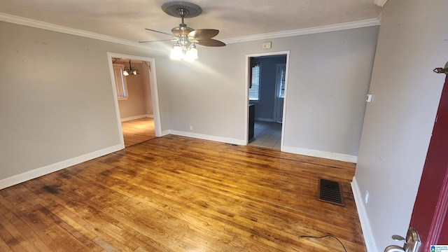 empty room with hardwood / wood-style floors, ceiling fan with notable chandelier, and crown molding