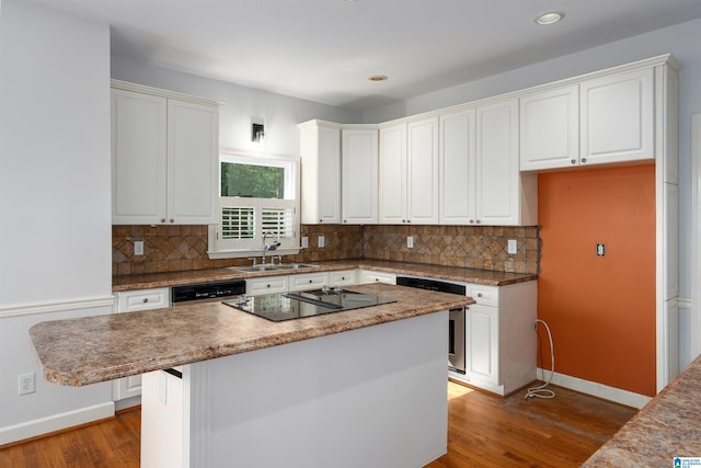 kitchen featuring black electric cooktop, sink, white cabinets, hardwood / wood-style floors, and a kitchen island