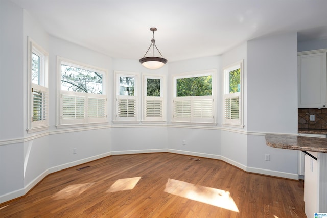 unfurnished dining area with a wealth of natural light and hardwood / wood-style floors