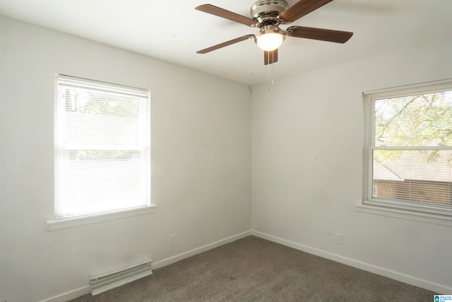 unfurnished room with plenty of natural light, dark carpet, and ceiling fan