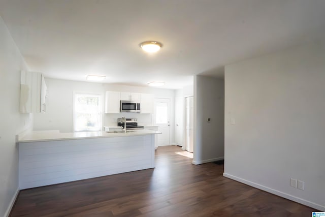 kitchen featuring kitchen peninsula, stainless steel appliances, sink, dark hardwood / wood-style floors, and white cabinetry