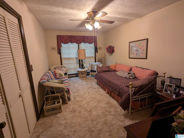 carpeted bedroom with ceiling fan, a textured ceiling, and a closet