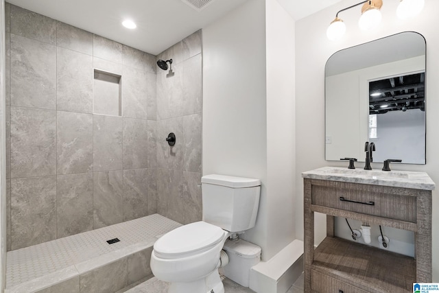 bathroom featuring tiled shower, vanity, and toilet