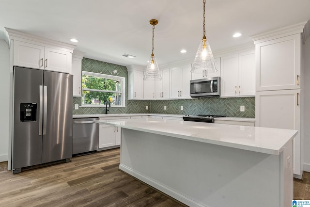 kitchen featuring white cabinets, appliances with stainless steel finishes, and pendant lighting