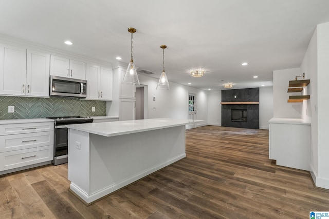 kitchen with appliances with stainless steel finishes, decorative light fixtures, white cabinetry, and dark wood-type flooring