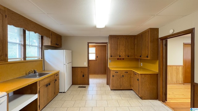 kitchen with wooden walls, white refrigerator, and sink