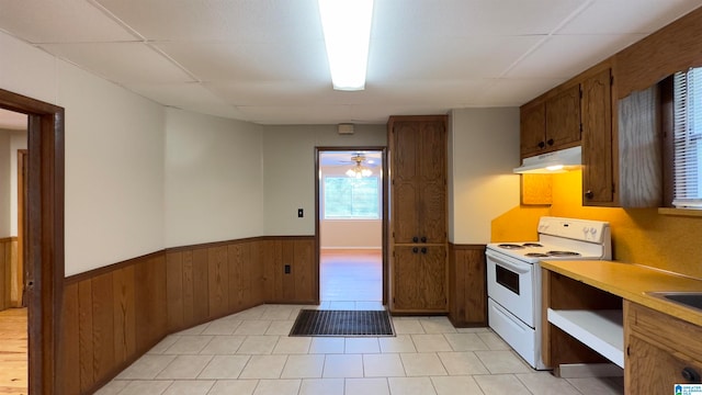 kitchen with white electric range, ceiling fan, and wooden walls