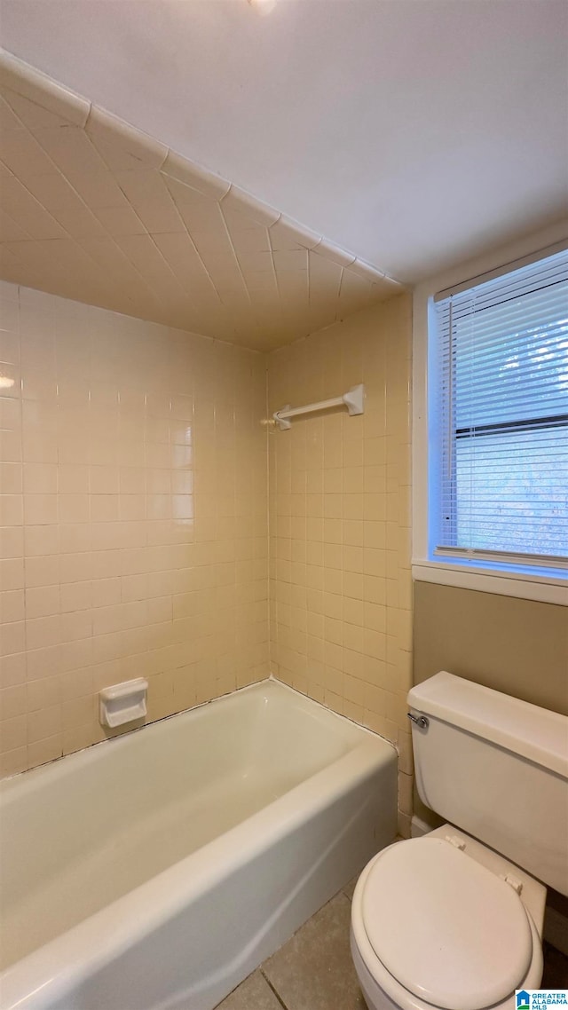 bathroom featuring toilet, tile patterned floors, and tiled shower / bath combo