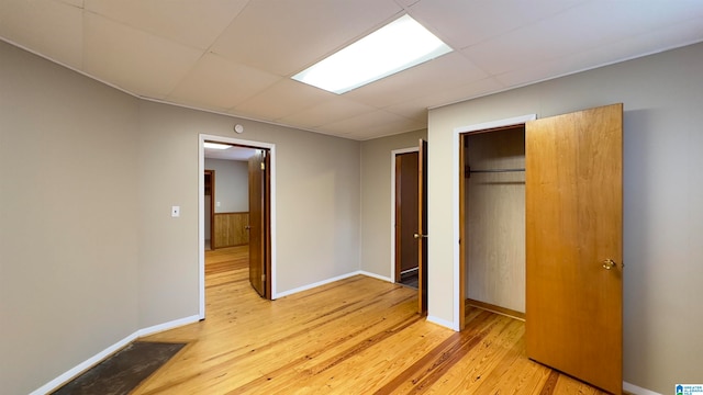 unfurnished bedroom featuring a closet, light hardwood / wood-style floors, and a drop ceiling