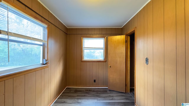 empty room with ornamental molding, dark hardwood / wood-style flooring, and wooden walls