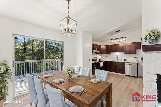 dining area featuring a chandelier, light hardwood / wood-style floors, sink, and vaulted ceiling