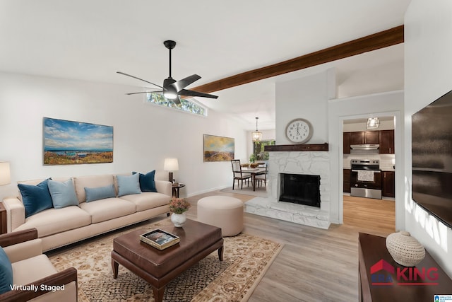 living room with ceiling fan, light hardwood / wood-style floors, a premium fireplace, and lofted ceiling with beams