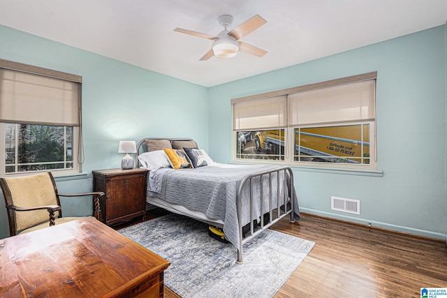 bedroom with hardwood / wood-style flooring, ceiling fan, and multiple windows