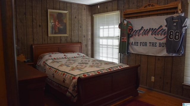 bedroom with wooden walls and dark hardwood / wood-style floors