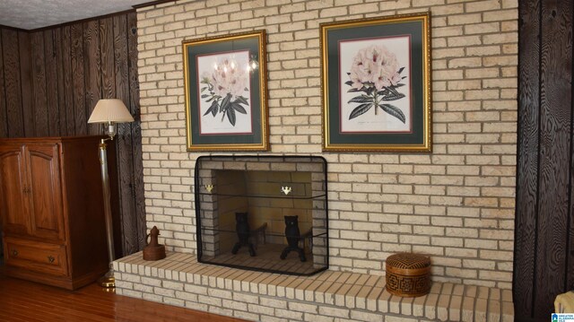 room details featuring wood-type flooring, a textured ceiling, and a brick fireplace