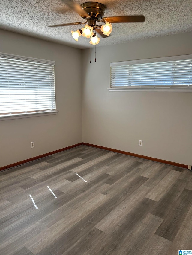 empty room with ceiling fan, hardwood / wood-style flooring, and a textured ceiling