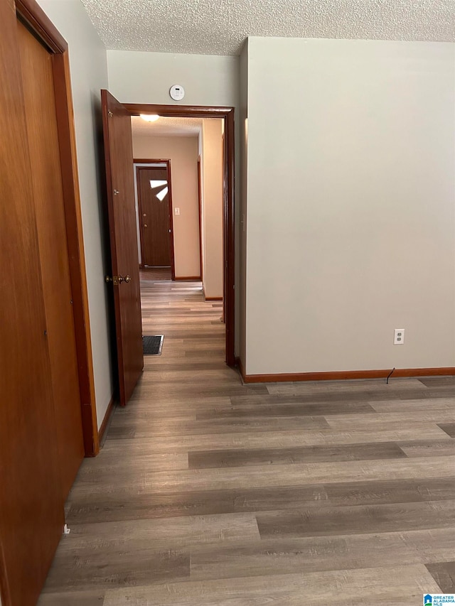 hall featuring light hardwood / wood-style flooring and a textured ceiling