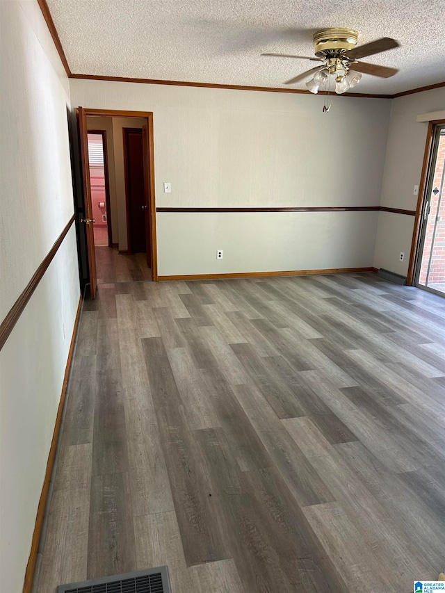 spare room with ceiling fan, ornamental molding, a textured ceiling, and hardwood / wood-style flooring