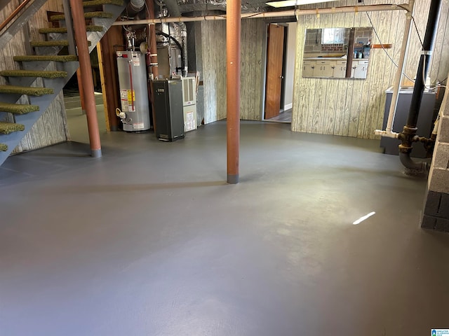 basement with heating unit, water heater, and wood walls