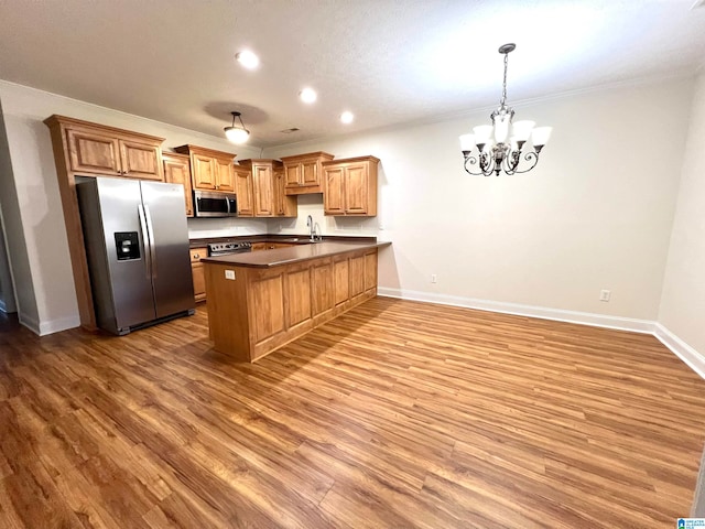 kitchen with kitchen peninsula, hardwood / wood-style floors, stainless steel appliances, and sink