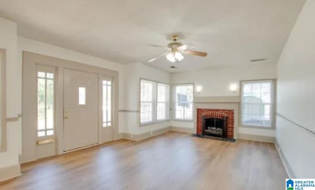 unfurnished living room with a fireplace, ceiling fan, plenty of natural light, and light hardwood / wood-style floors