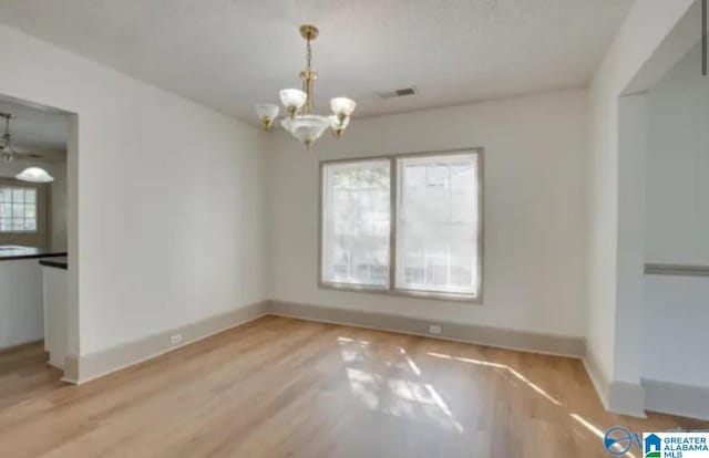 unfurnished dining area with a wealth of natural light, an inviting chandelier, and light wood-type flooring