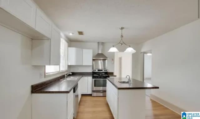 kitchen with white cabinetry, a center island, stainless steel appliances, and wall chimney range hood