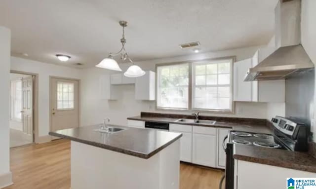 kitchen featuring stainless steel range with electric stovetop, wall chimney range hood, sink, a kitchen island, and white cabinetry