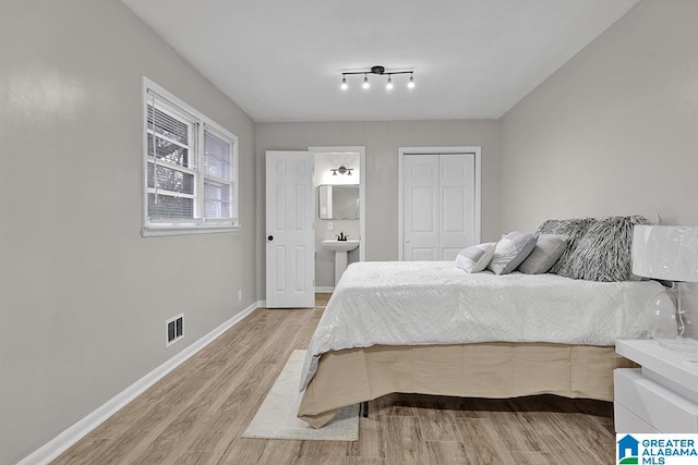 bedroom with hardwood / wood-style flooring, ensuite bath, a closet, and sink