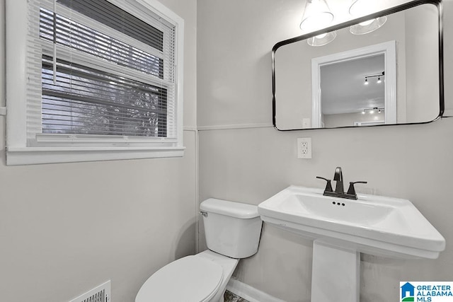 bathroom featuring toilet, sink, and a wealth of natural light