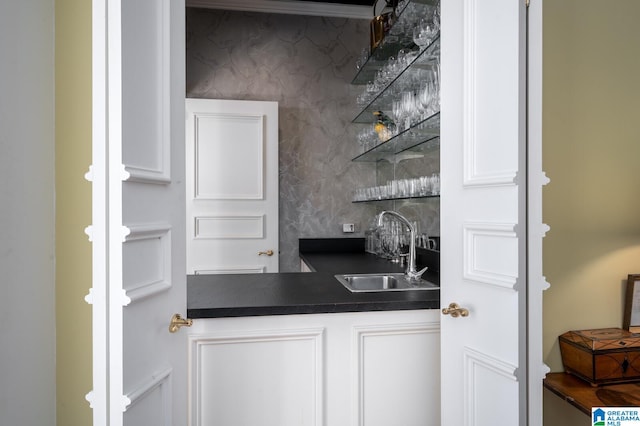 bar with decorative backsplash, sink, and white cabinets