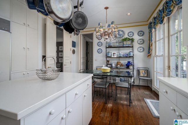 kitchen with an inviting chandelier, dark hardwood / wood-style flooring, decorative light fixtures, white cabinets, and ornamental molding