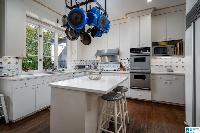 kitchen featuring a center island, dark hardwood / wood-style floors, appliances with stainless steel finishes, tasteful backsplash, and white cabinetry