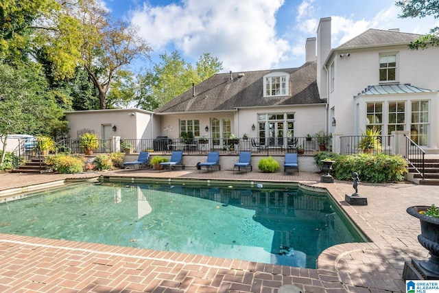 rear view of property featuring a fenced in pool and a patio area