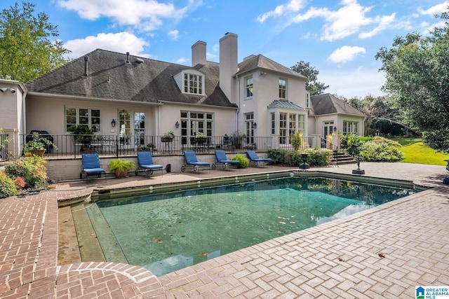 back of property with a fenced in pool and a patio