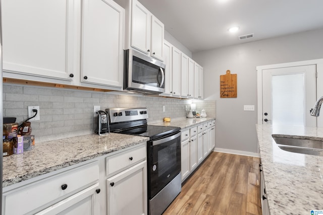 kitchen with light wood-type flooring, white cabinetry, sink, and appliances with stainless steel finishes