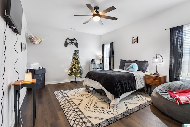 bedroom featuring dark hardwood / wood-style flooring, multiple windows, and ceiling fan