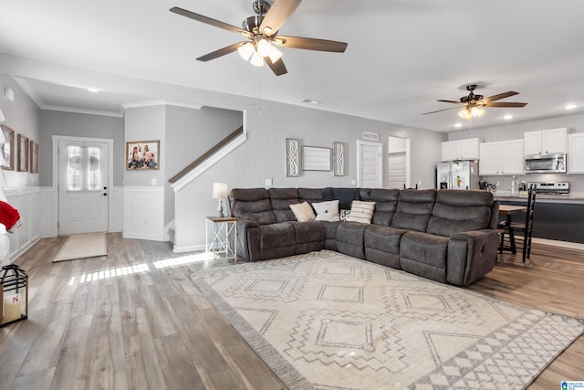 living room featuring ceiling fan, light hardwood / wood-style floors, and crown molding