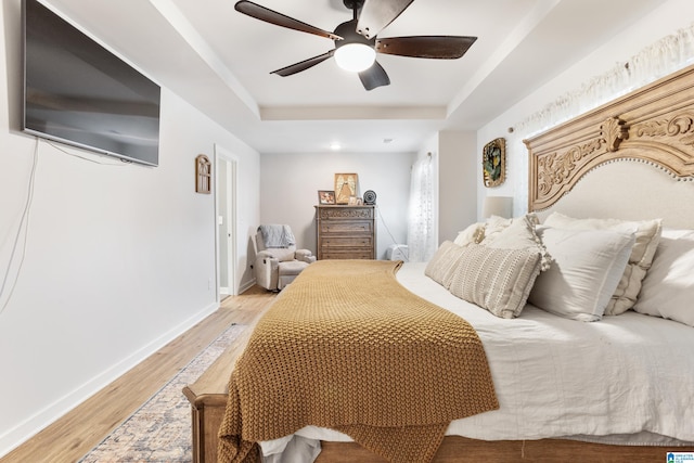 bedroom with a tray ceiling, ceiling fan, and light hardwood / wood-style floors