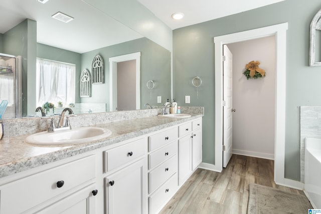 bathroom with a bathing tub, vanity, and hardwood / wood-style flooring