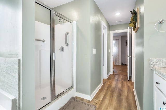 bathroom with wood-type flooring, vanity, and an enclosed shower