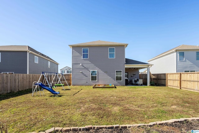 back of house with a yard and a playground