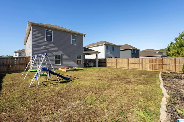 rear view of property with a playground and a yard