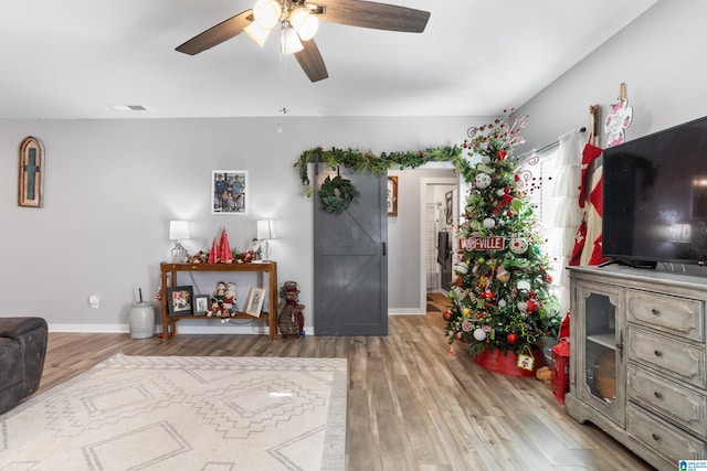 living room with a barn door, ceiling fan, and hardwood / wood-style floors