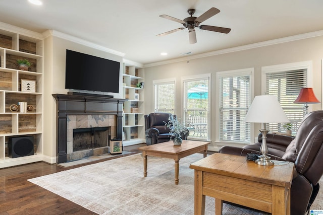 living room featuring ceiling fan, a fireplace, wood-type flooring, and ornamental molding